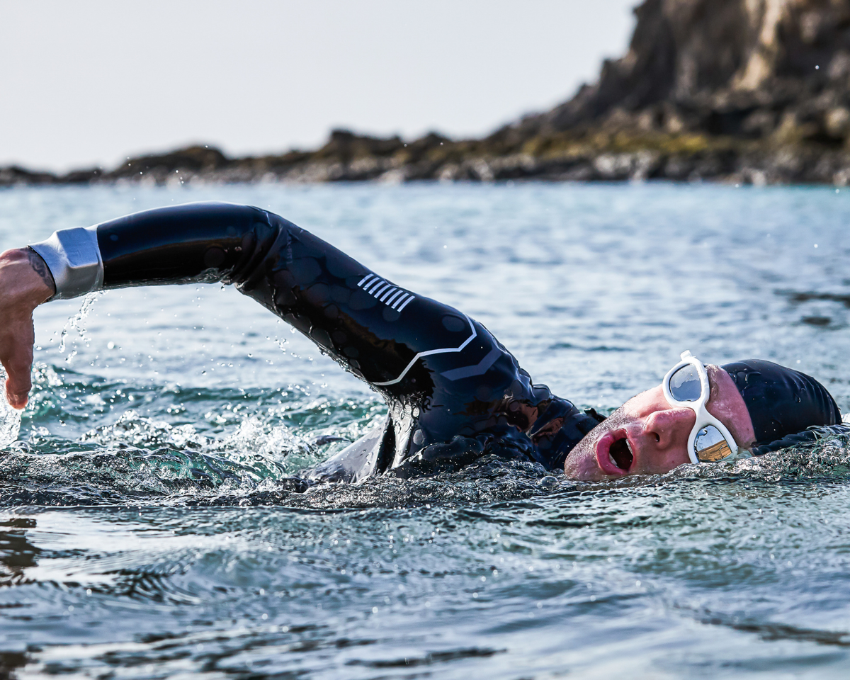 Person swimming in open water with sunglasses on, wearing the Agile wetsuit.